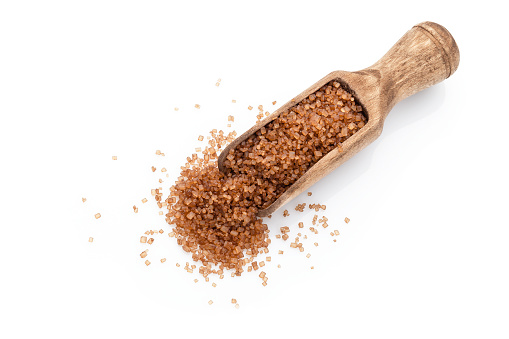 Top view of a wooden measuring spoon filled with brown sugar crystals isolated on white background. High key DSRL studio photo taken with Canon EOS 5D Mk II and Canon EF 100mm f/2.8L Macro IS USM