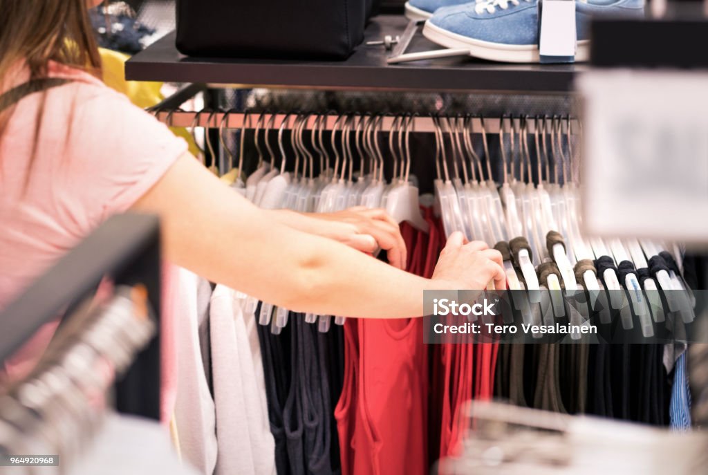 Woman Looking At Clothes In A Rack In Fashion Store Female Customer  Shopping Sale And Clearance In Clothing Boutique Stock Photo - Download  Image Now - iStock