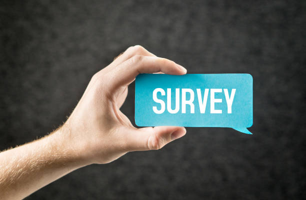 istock Survey. Giving feedback, market research, questionnaire, user experience and review concept. Hand holding cardboard paper speech bubble. 964921882