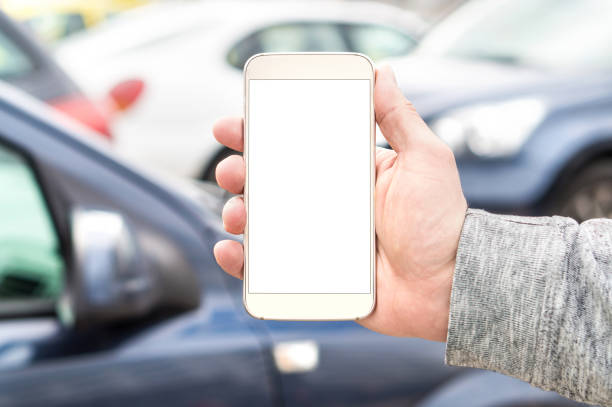 istock Man holding smartphone with empty blank white screen. Many cars or traffic in background. Mobile phone in hand. Template for navigation, parking or ride share app. 964921972