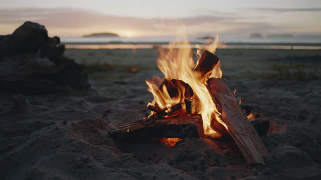 SLO MO. A campfire burns on a scenic Tofino beach at sunset.