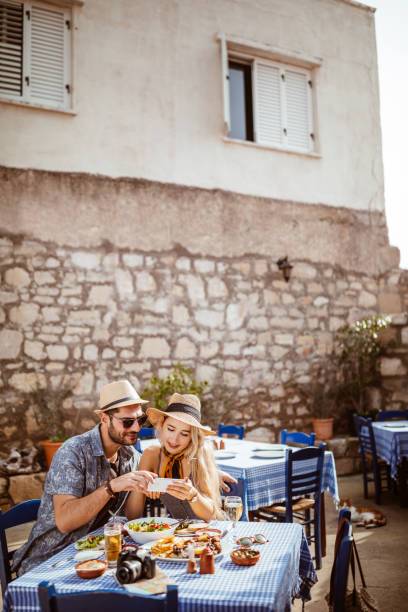 istock Young tourists on vacations using smartphone at traditional Greek tavern 964944676