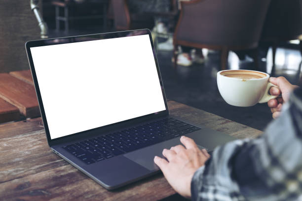 istock Mockup image of a woman using laptop with blank white desktop screen while drinking hot coffee in cafe 964949092