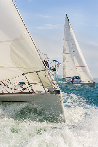 Two sailing boats, sailboats or yachts racing at sea