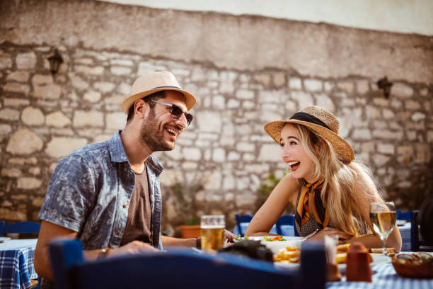 Tourists eating lunch at traditional stonebuilt restaurant in the Mediterranean Young tourists couple having fun eating Mediterranean food at traditional rustic restaurant in Spain 2655 stock pictures, royalty-free photos & images