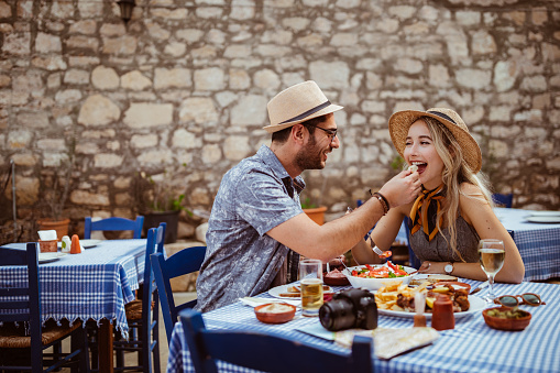 Young tourists couple on summer holidays in the Mediterranean eating traditional food at stonebuilt restaurant