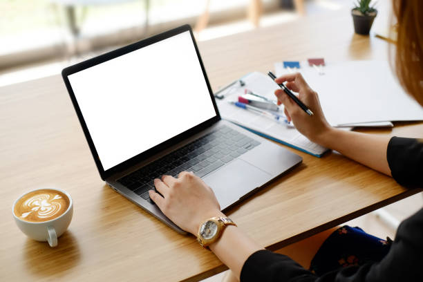 Mockup laptop computer using by business woman on workplace with blank empty screen display and coffee latte on work table.
