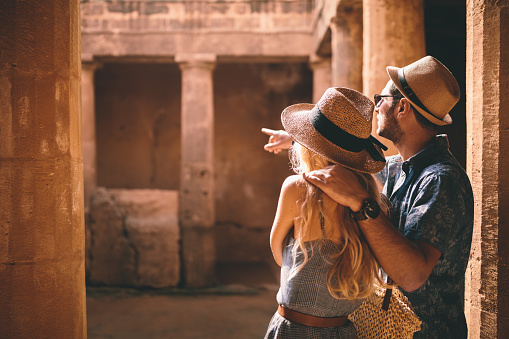 Young tourists couple on summer holidays visiting ancient archaeological site with stone columns in Egypt