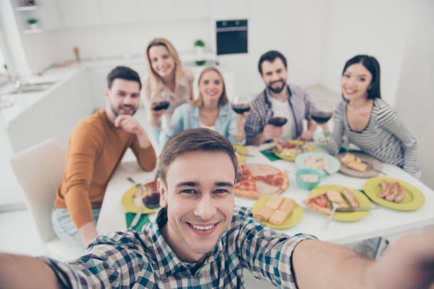istock Handsome, attractive, stylish man making self portrait with best friends on blurred background sitting at the table holding glasses with red wine, celebrating holiday indoor 964962702