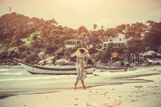 woman in a boho dress walking on the tropical beach