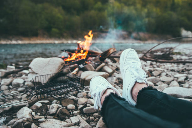 istock person resting near riverside with camp fire. hiking concept 964981234