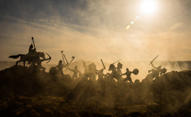 istock Medieval battle scene with cavalry and infantry. Silhouettes of figures as separate objects, fight between warriors on sunset foggy background. 964984638