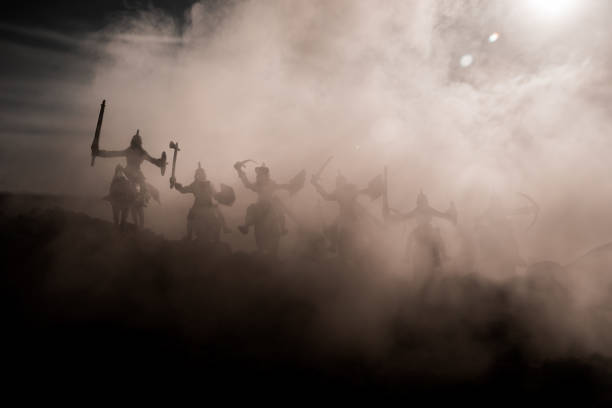 istock Medieval battle scene with cavalry and infantry. Silhouettes of figures as separate objects, fight between warriors on sunset foggy background. 964984670
