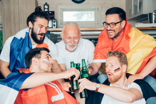 istock People of all ages having celebratory toast while watching soccer game 964985090