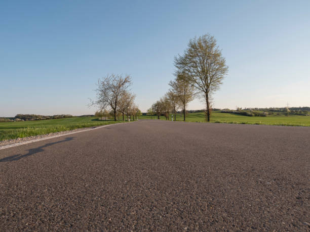 istock empty countryside rural road in spring season background framed by trees 964989956