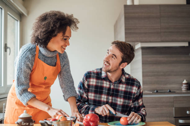 istock Happy couple chopping vegetables and looking at each other in the kitchen 964999562