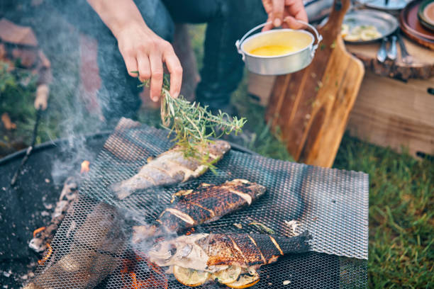 voorbereiding van vis voor het koken boven open kampvuur - barbecue maaltijd fotos stockfoto's en -beelden