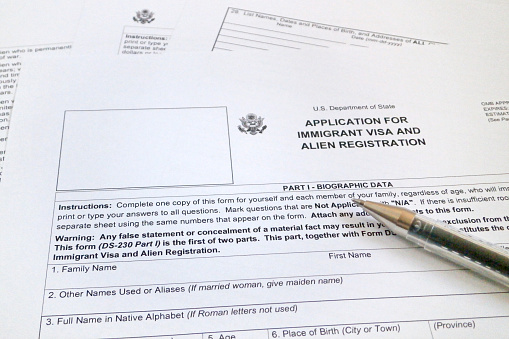 a ballpoint pen on the top of an application form for immigrant visa and alien registration.