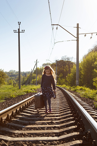 The girl with a suitcase goes by railroad.