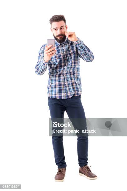 Bearded Hipster Man Twirling Mustache Using Mobile Phone Reflection As Mirror Stock Photo - Download Image Now