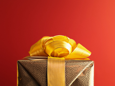 Three gifts in wrapping papers with bows on a wooden background.