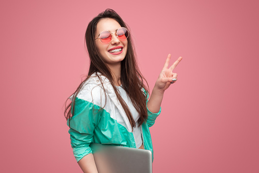 Chica hipster con portátil mostrando dos dedos photo