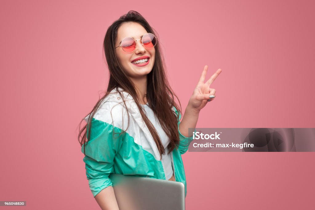 Fille de hipster avec ordinateur portable montrant deux doigts - Photo de Adolescent libre de droits
