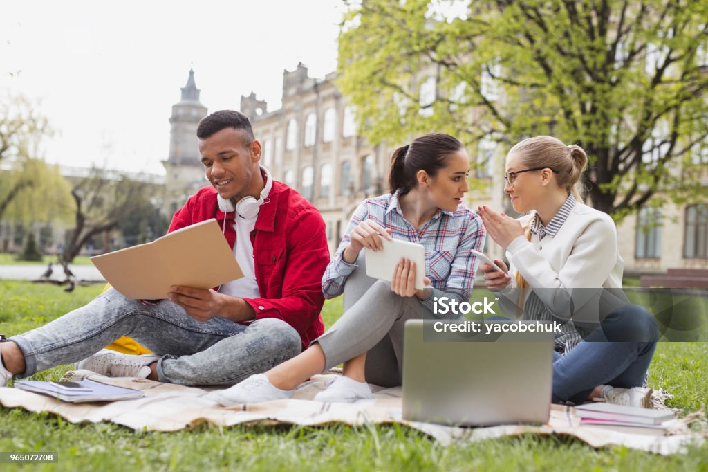 Exchange students chatting with each other spending free time together Exchange students. Exchange students feeling amazing while chatting with each other spending their free time together Credit Card Stock Photo