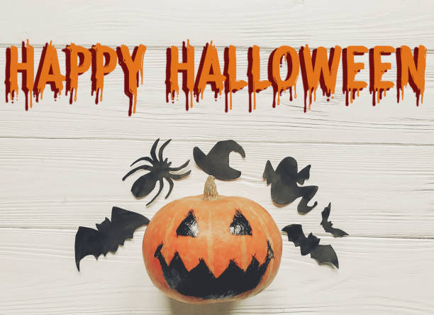 istock happy halloween text flat lay. jack lantern pumpkin with witch ghost bats and spider black decorations on white wooden background top view, space for text. seasonal greetings. 965081532