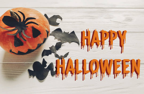 istock happy halloween text flat lay. jack lantern pumpkin with witch ghost bats and spider black decorations on white wooden background top view, space for text. seasonal greetings. 965081734