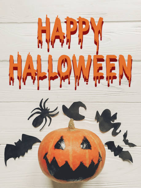 istock happy halloween text. jack lantern pumpkin with witch ghost bats and spider black decorations on white wooden background top view. seasonal greetings, space text 965082072