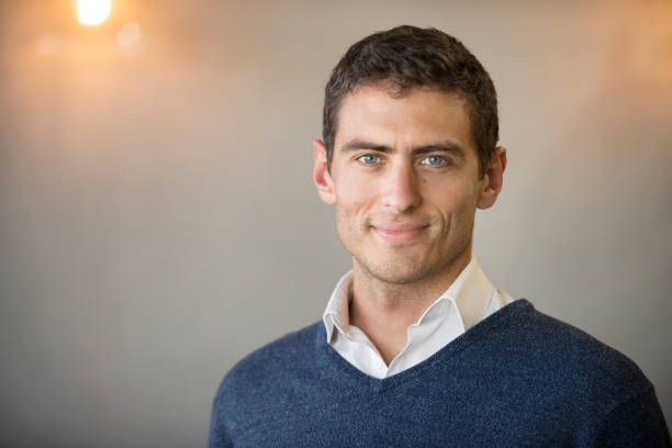 Shoulders up portrait of businessperson looking at camera standing in his office