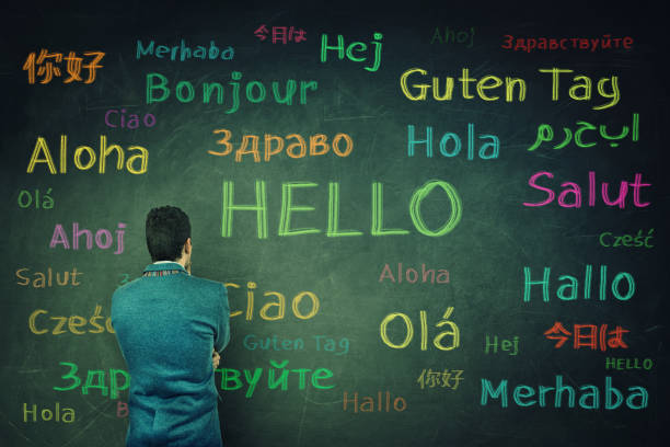 Opportunity for learning Rear view of a puzzled businessman in front of a huge chalkboard written with the word hallo in different languages and colors. Opportunity for learning many languages for students. language photos stock pictures, royalty-free photos & images