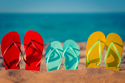 Adult and child footwear of different sizes lies beside a beautiful ocean.