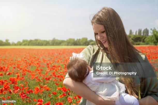 Happy Young Mother Holding Her Baby In A Poppy Field Stock Photo - Download Image Now