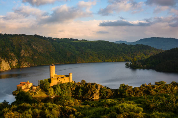 initialement situé sur un promontoire dominant les gorges de la loire, le château de grangent se trouve sur une île depuis la construction du barrage de grangent en 1957. - sunset dusk mountain reservoir photos et images de collection