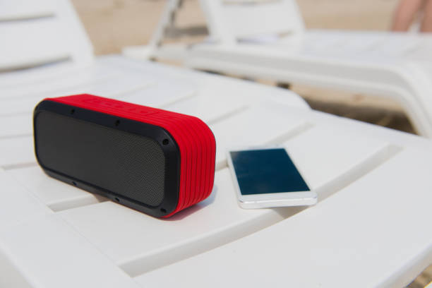 Portable speaker and smartphone outdoors. Audio usb bluetooth wireless electronics at chaise longue