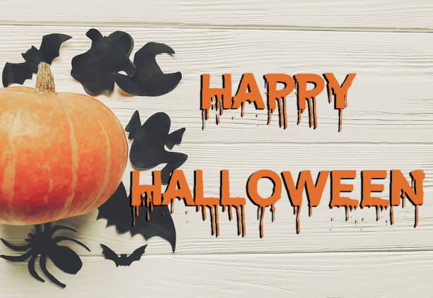 istock happy halloween text flat lay.  pumpkin with witch ghost bats and spider black decorations on white wooden background top view with space for text. cutouts for autumn holiday 965118028