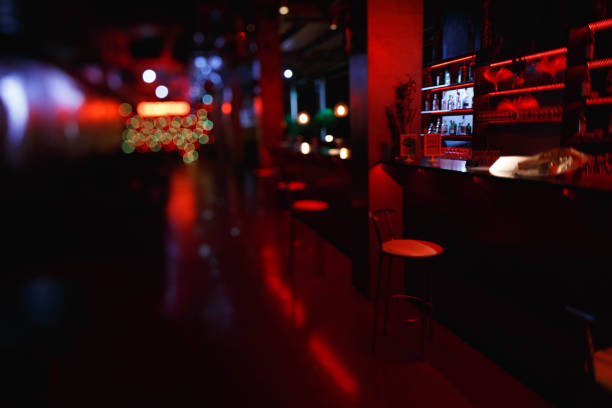 interni e mobili del bar notturno con illuminazione rossa. gli sgabelli da bar sono al bar, fotografati sul tilt-shift dell'obiettivo - glass bar relaxation red foto e immagini stock