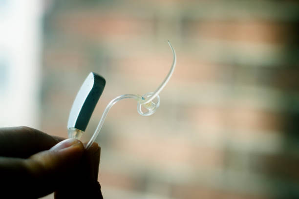 Deaf senior citizen man wearing modern digital high technology hearing aid in ear.