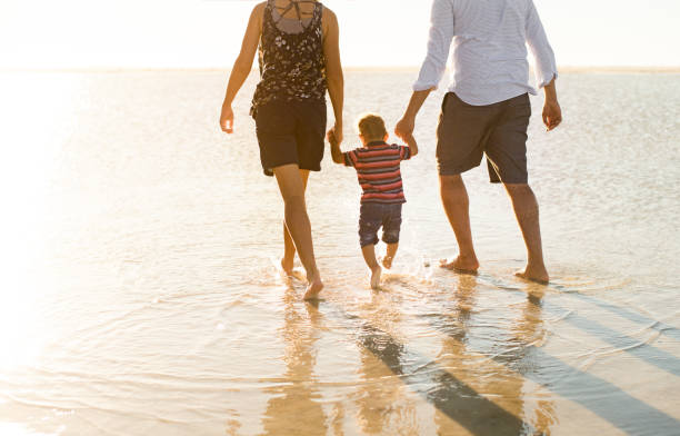istock Beautiful family holding hands walking on the beach 965139552