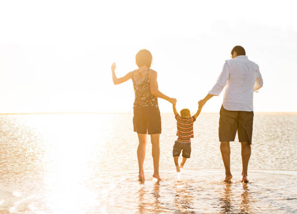 istock Beautiful family holding hands walking on the beach 965139612