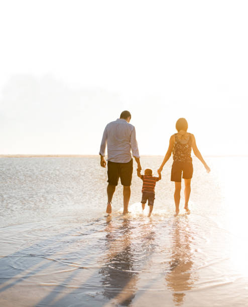 Beautiful family holding hands walking on the beach Mixed race family walking on the beach outdoors in the sun, holding hands beauty in nature vertical africa southern africa stock pictures, royalty-free photos & images