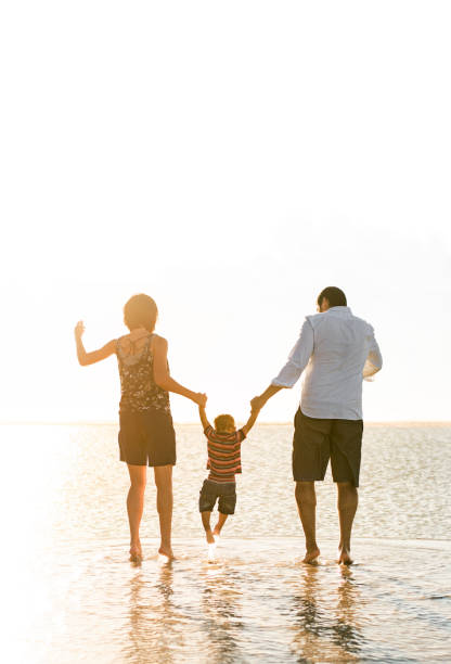 istock Beautiful family holding hands walking on the beach 965139766