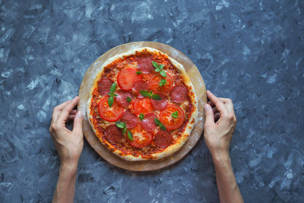 istock Homemade pepperoni pizza on a blue-grey kitchen table. Top view 965150996
