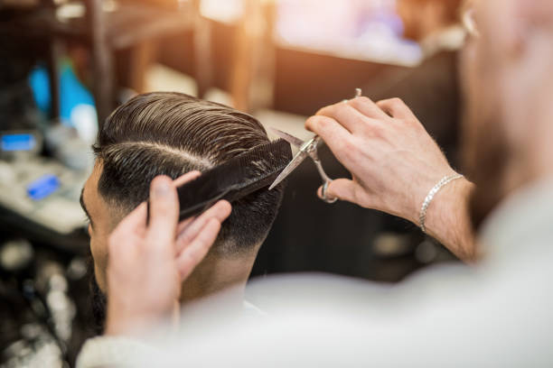 Rear view of young man getting a modern haircut. stock photo