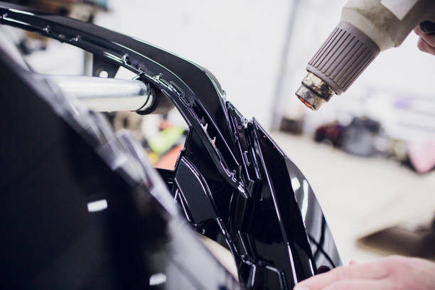 istock Worker hands installs car paint protection film wrap bumper 965187488