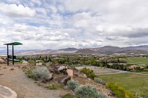 Wide view of valley, hills and city of Reno, Nevada from a lookout with a covered bench.