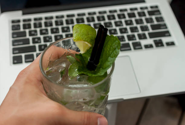glass of mojito in male hand on laptop background