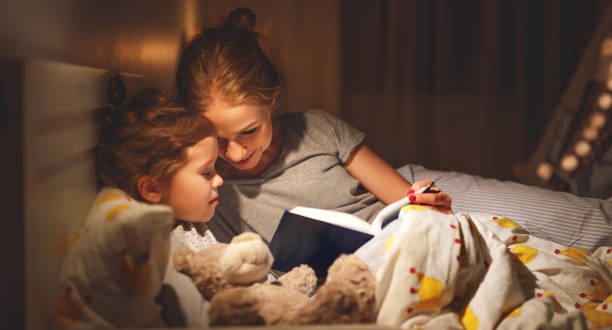 istock mother and child reading book in bed before going to sleep 965212854